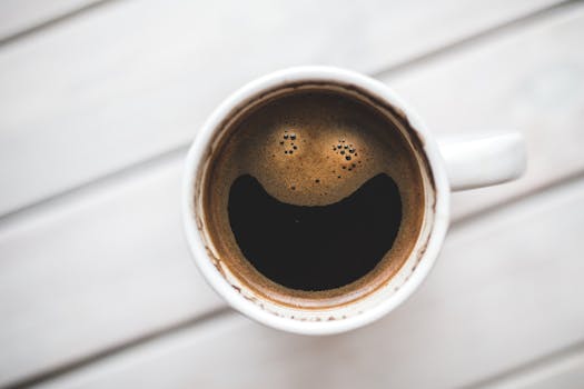 A coffee cup with a smiling face pattern on a wooden table for mom  finding small wins in motherhood.